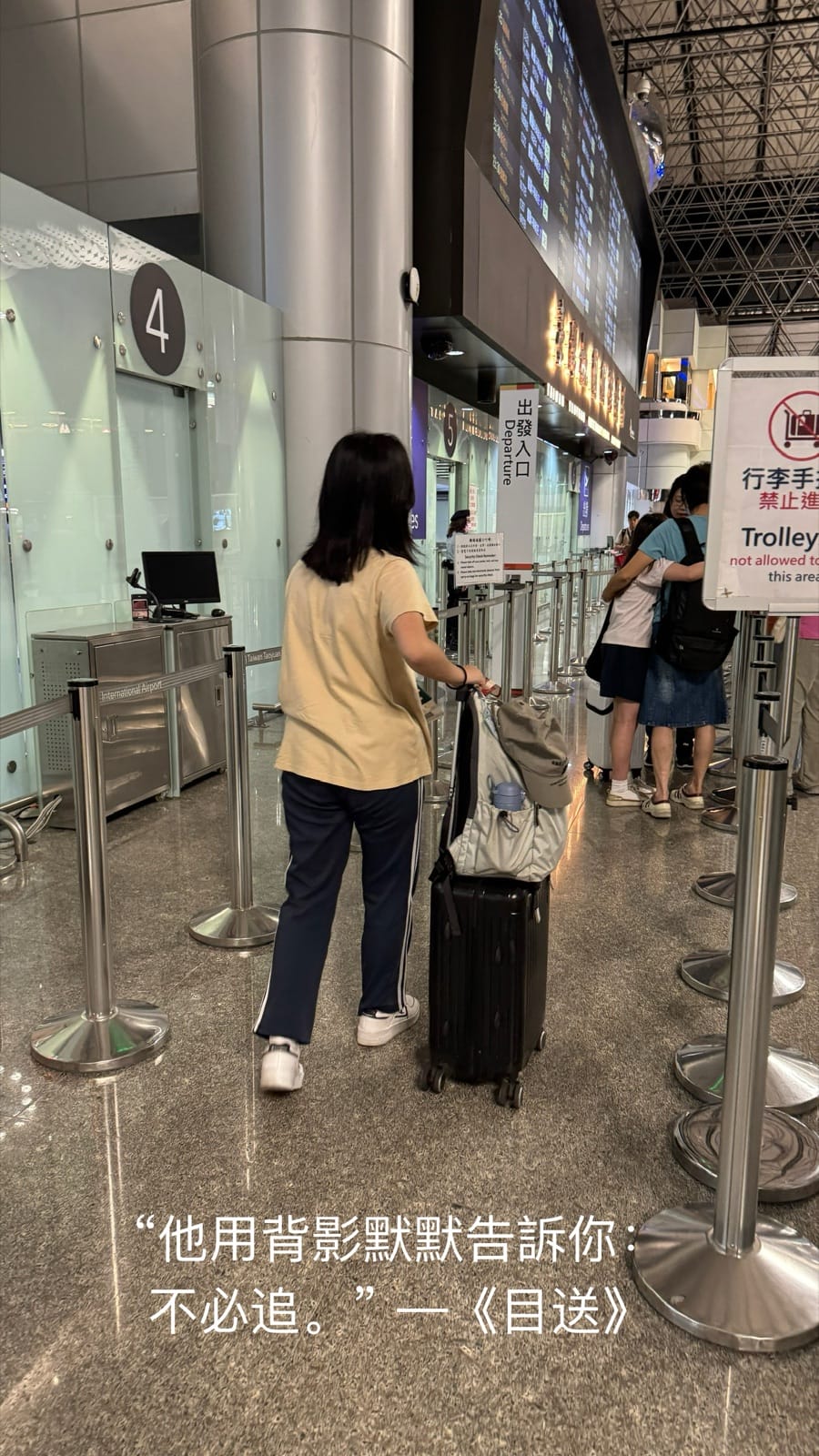 一名少女拉著行李箱走向機場出境通道